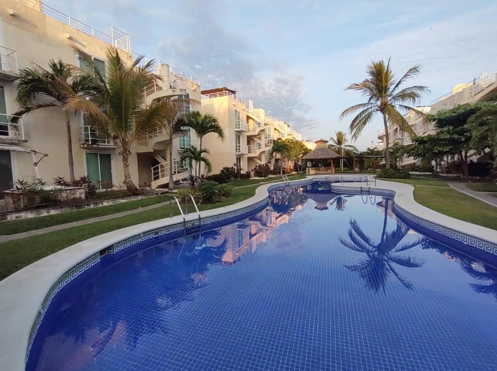 une grande piscine avec des palmiers et des bâtiments dans l'établissement depto relajante Diamante, à Acapulco