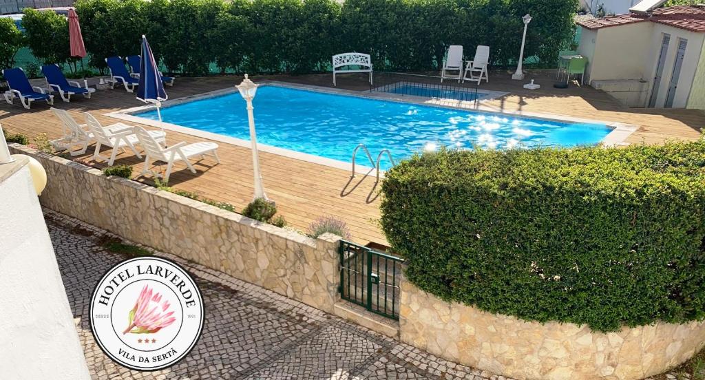 a swimming pool with chairs and a sign in front of it at Hotel Larverde in Sertã