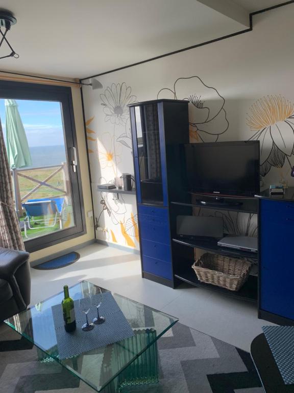 een woonkamer met een tv en een glazen tafel bij Appartement Wimereux - Opaalkust met frontaal zeezicht in Wimereux