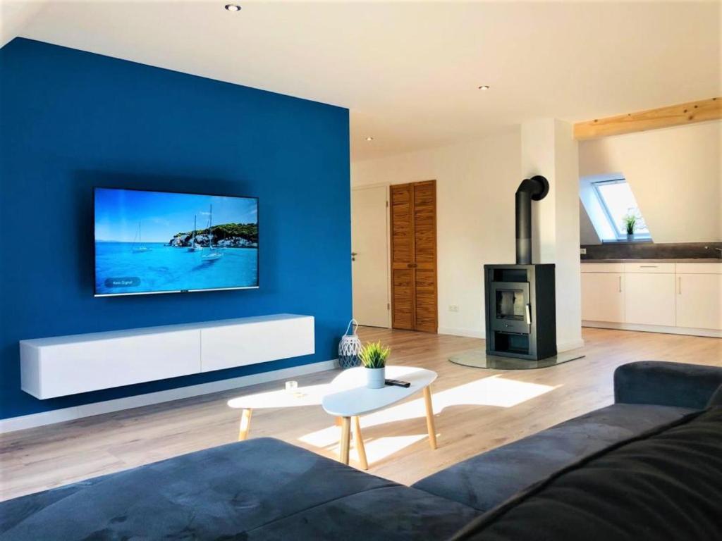 a living room with a blue wall with a fireplace at NEU! Moderne FeWo Ostseebrise Fehmarn in Petersdorf auf Fehmarn