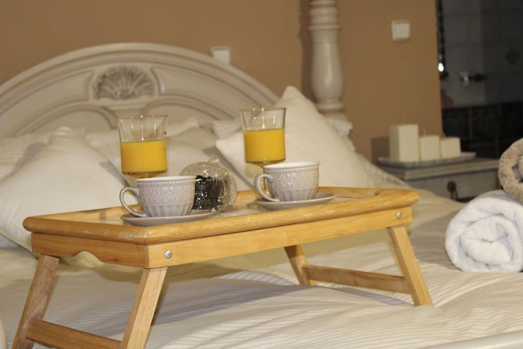 una bandeja con dos tazas y dos vasos de zumo de naranja en una cama en Άνεση και ήρεμία en Oropo
