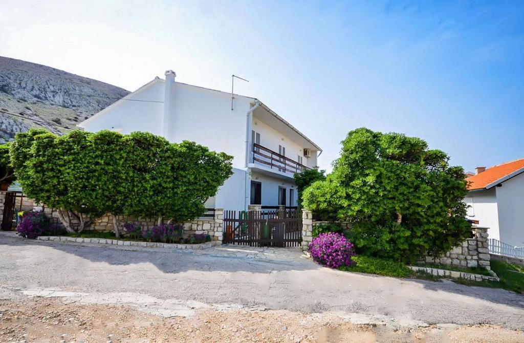 a white house with bushes and a fence at Apartments Jelica in Pag