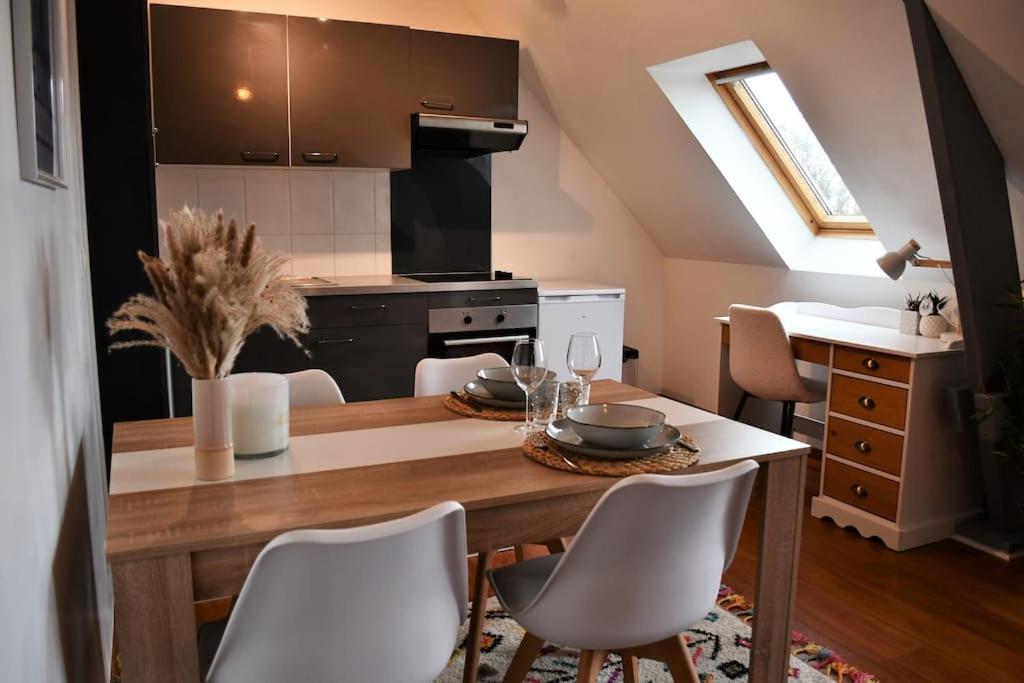 a kitchen with a wooden table with chairs and a dining room at Cœur des chevaux in Deauville