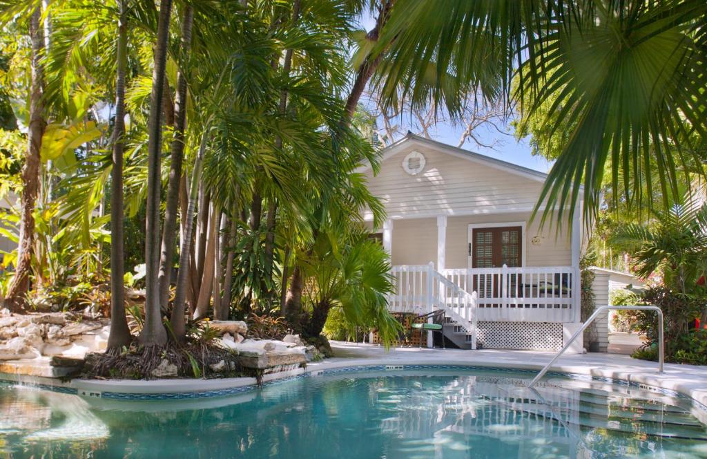 a swimming pool in front of a house with palm trees at Westwinds Inn in Key West