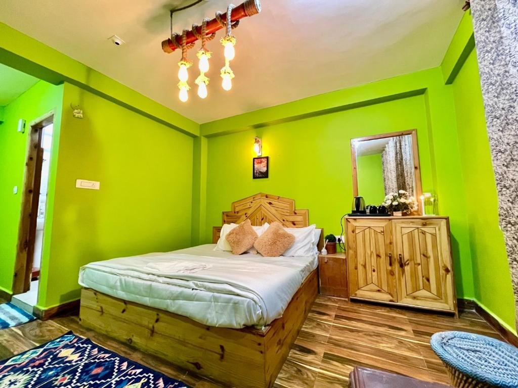 um quarto com paredes verdes e uma cama num quarto em Attic Monkey Cafe & Rooms em Manali