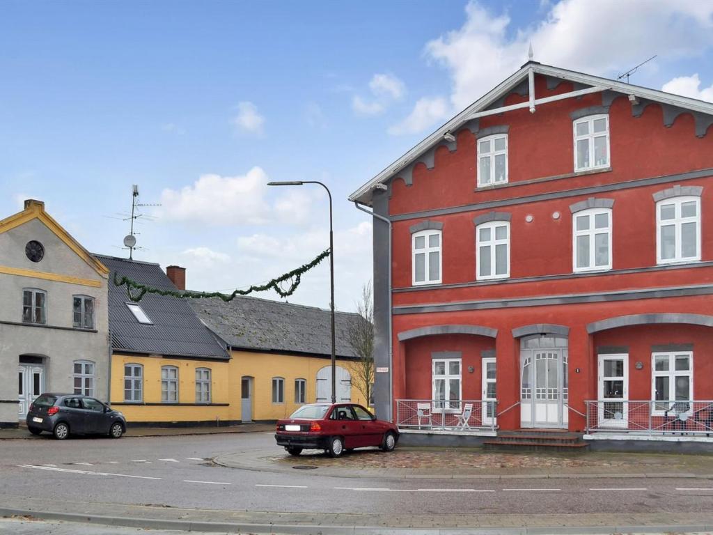 a red house with a red car parked in a street at Apartment Esja - 22km from the sea in Western Jutland by Interhome in Bredebro