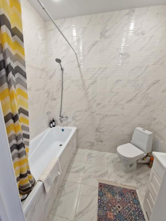 a white bathroom with a tub and a toilet at INJU апартаменты in Taldykolʼ