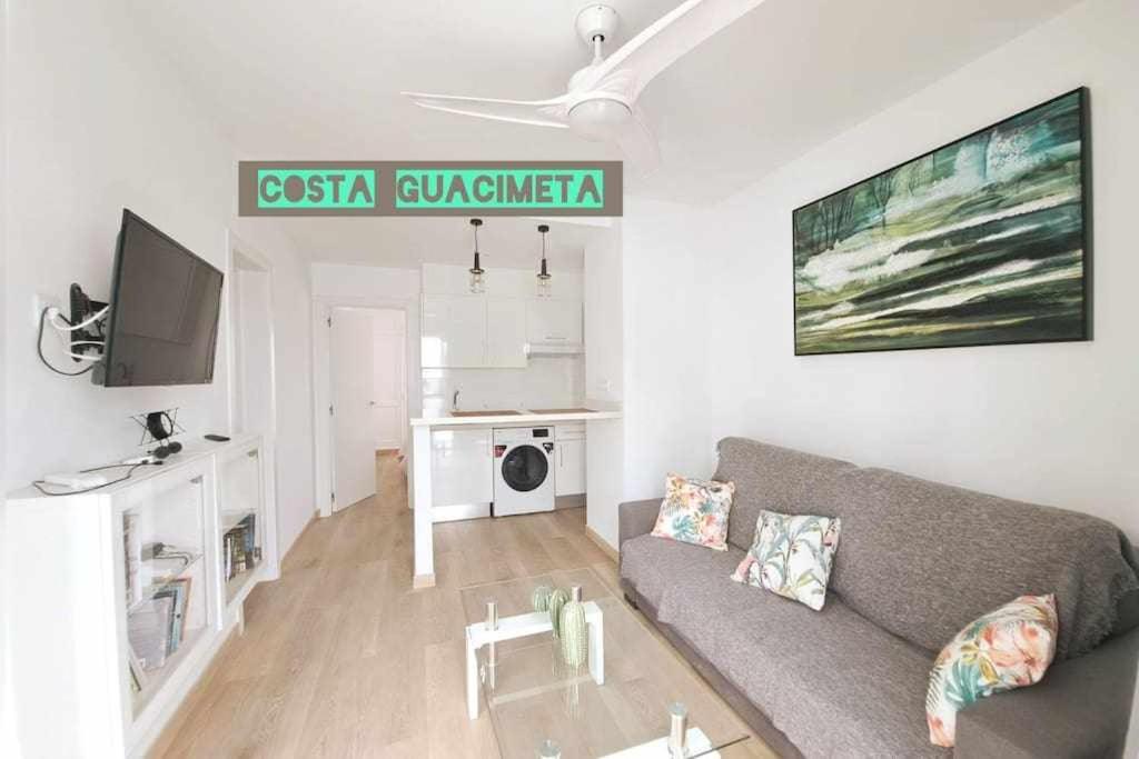 een woonkamer met een bank en een tv bij Costa Guacimeta Apartment in Los Pocillos