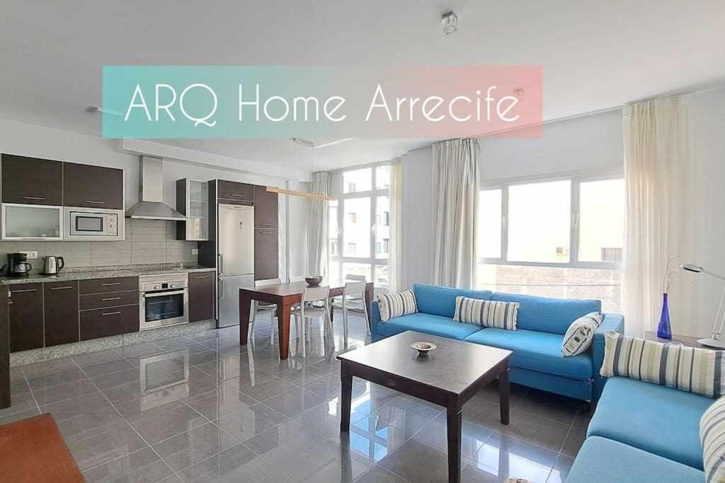 a living room with a blue couch and a kitchen at ARQ Home Arrecife in Arrecife
