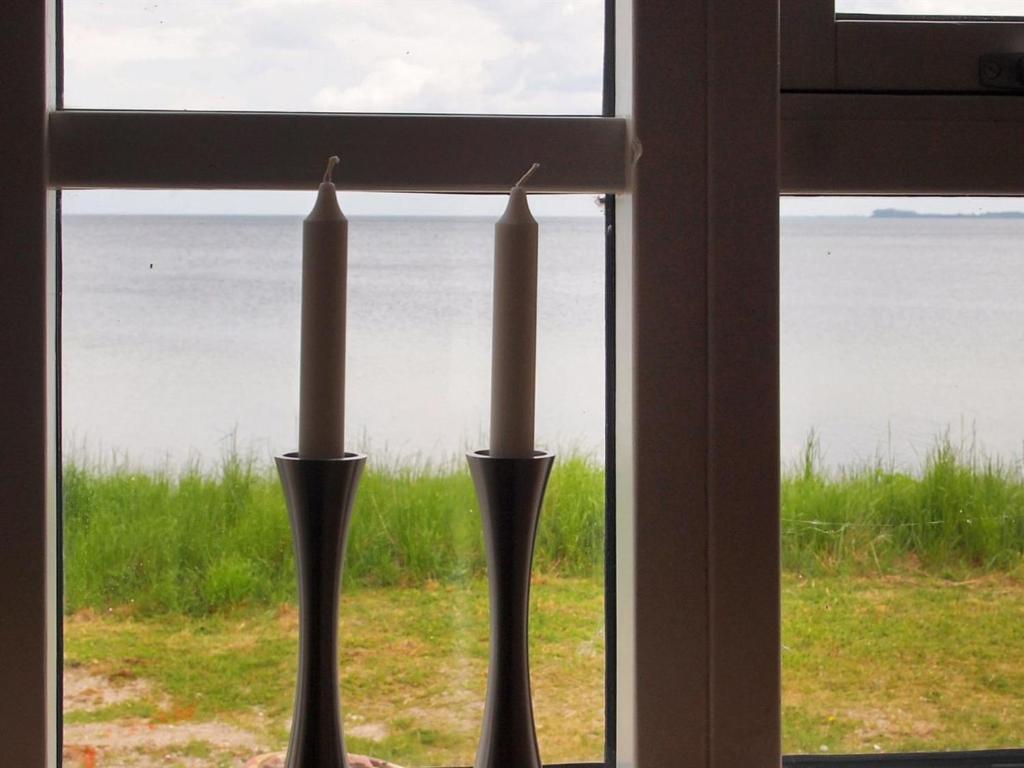duas velas numa janela com vista para o oceano em Holiday Home Udder - 50m to the inlet in SE Jutland by Interhome em Aabenraa