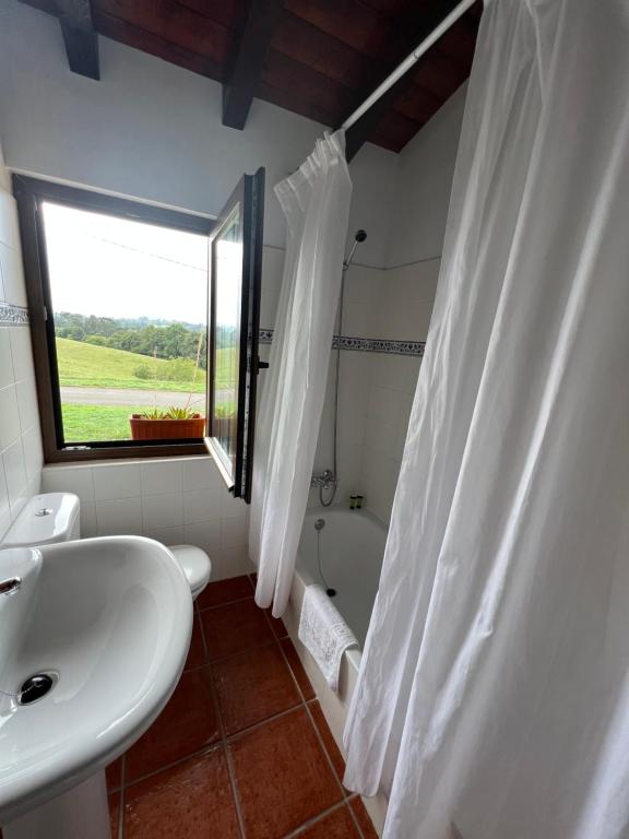 a bathroom with a sink and a toilet and a window at Posada La Vieja Escuela in La Revilla