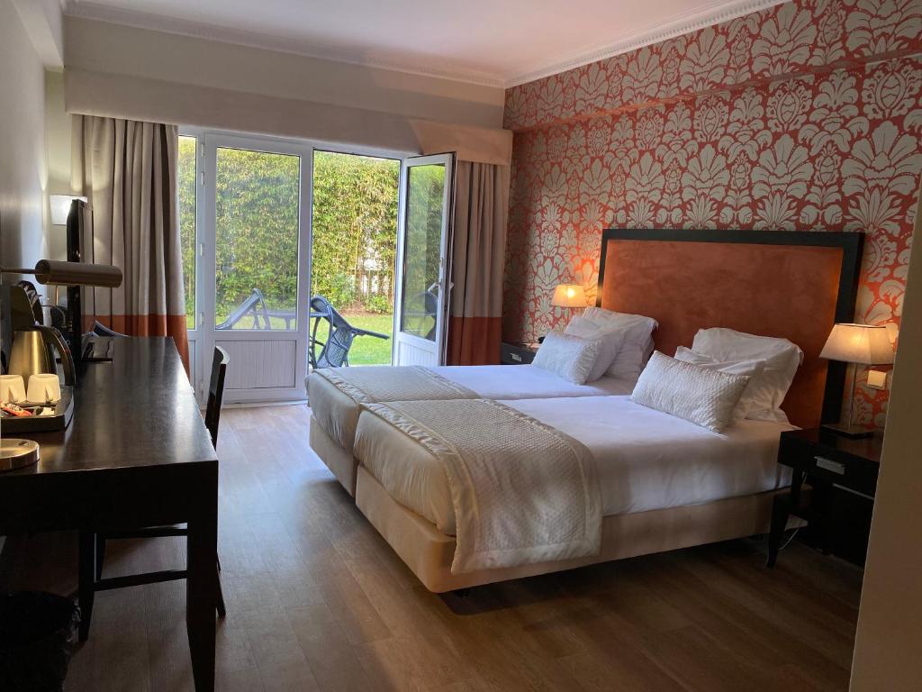 a bedroom with a bed and a desk and a window at Hotel Inglaterra - Charme & Boutique in Estoril