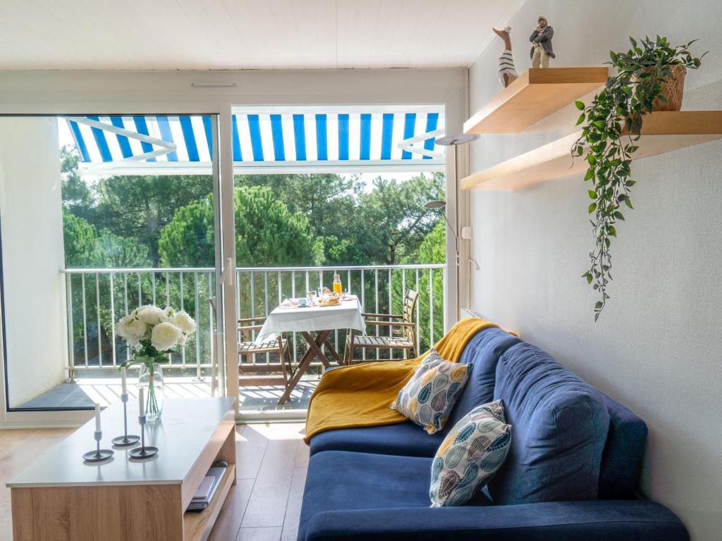ein Wohnzimmer mit einer blauen Couch und einem Balkon in der Unterkunft Apartment L'Ermitage-1 by Interhome in Saint-Brévin-lʼOcéan