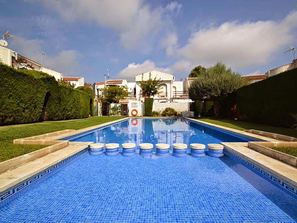 a large blue swimming pool with white stools around it at Villa Casalot 9 by Interhome in Miami Platja