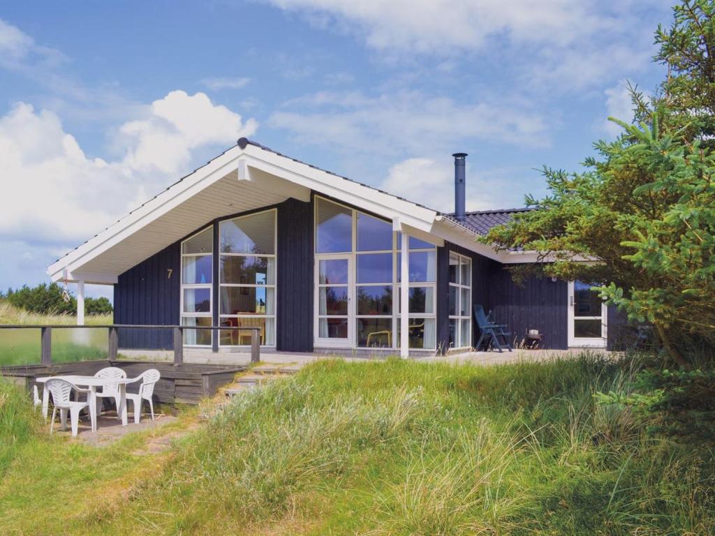 una casa azul con porche y sillas en Holiday Home Griselda - 700m from the sea in NW Jutland by Interhome en Torsted
