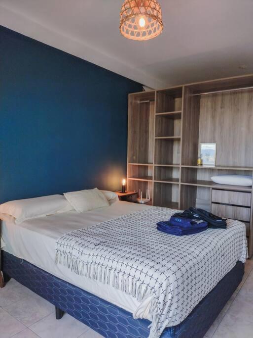 1 dormitorio con 1 cama grande y pared azul en Mate de Luna Estrella - 3 pax en San Miguel de Tucumán