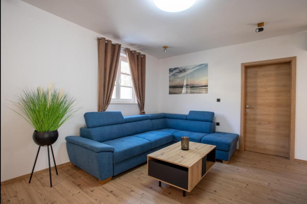 a living room with a blue couch and a table at Landena Apartments Lendava in Lendava