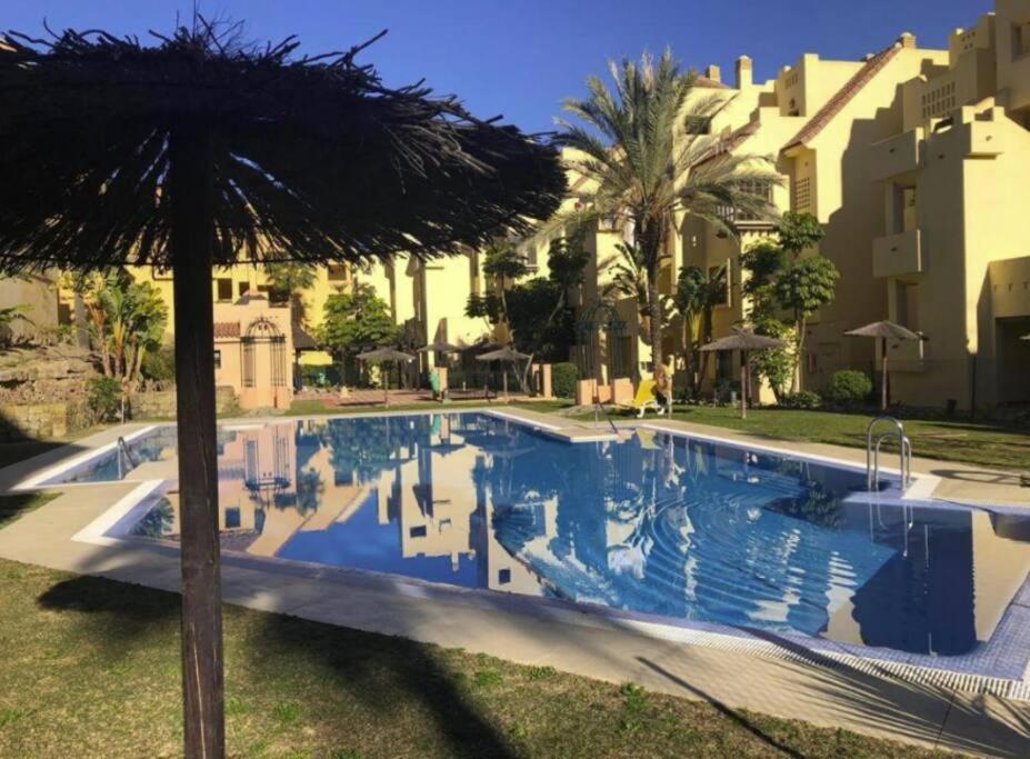 a swimming pool with an umbrella and some buildings at CT 199 - Duquesa Village in Manilva