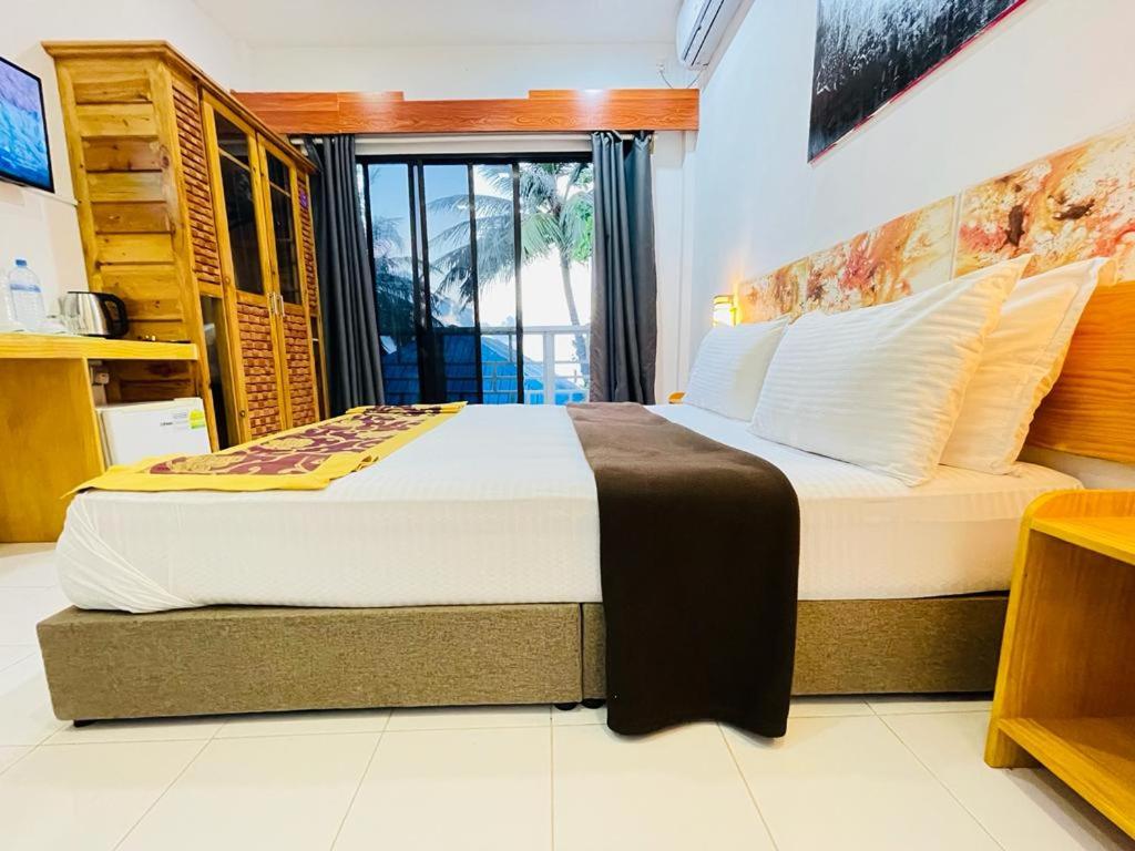a bedroom with two beds and a window at Paradise Retreat, Maafushi in Maafushi