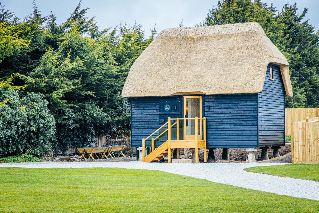 a blue hut with a thatched roof and a staircase at The Granary in Canterbury