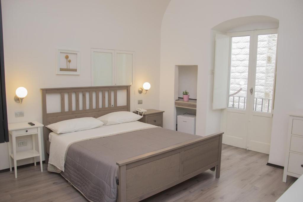 - une chambre blanche avec un grand lit et une fenêtre dans l'établissement B&B Cemener, à Ruvo di Puglia