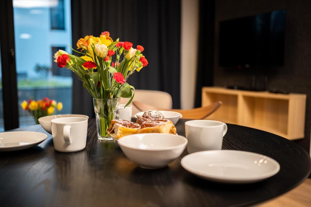 una mesa con un jarrón de flores y una mesa con platos en Apartament No1 Wyszyńskiego, en Wroclaw