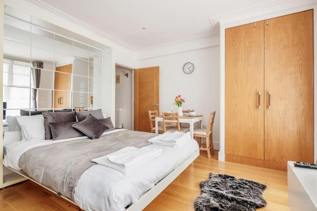 a white bedroom with a large bed and a table at The Hyde Park Corner in London