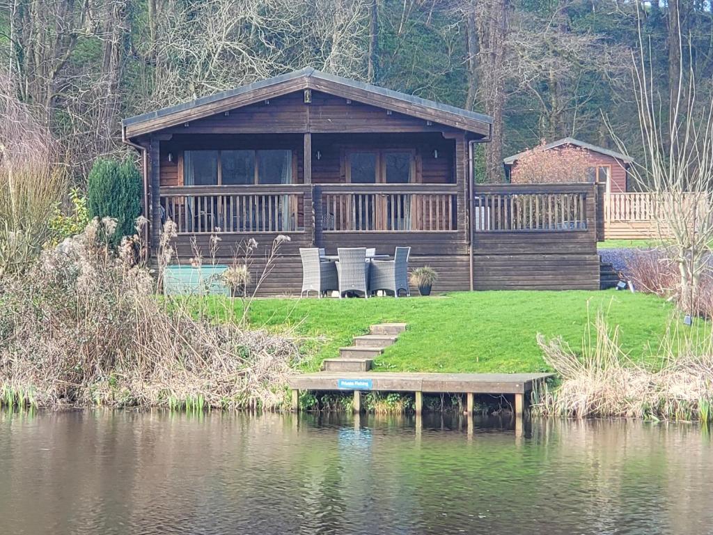 a log cabin with a dock next to a body of water at Immaculate 2-Bed Lodge Next To Lake in Preston
