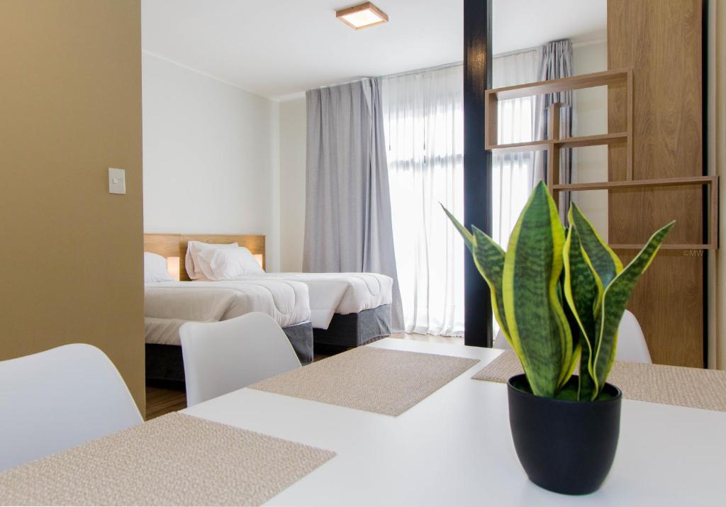 烏斯懷亞的住宿－Criollos Apartamentos，一间设有两张床的房间和一张桌子上的盆栽植物