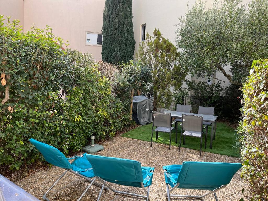 d'une terrasse avec des chaises et une table dans le jardin. dans l'établissement Studio en rez de jardin plage de Portissol, à Sanary-sur-Mer