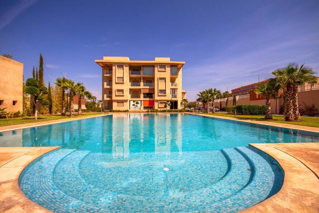 a large swimming pool in front of a building at Appartement luxueux Coralia avec piscine in Marrakech