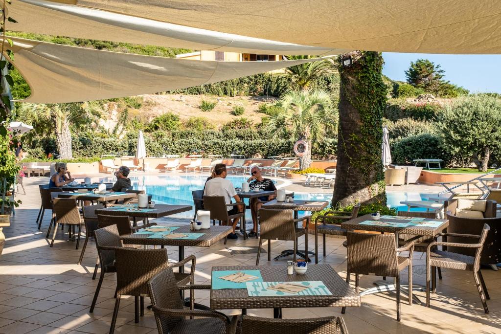 サンタ・テレーザ・ガッルーラにあるホテル コララーロのテーブルと椅子のあるレストラン、プールを提供しています。