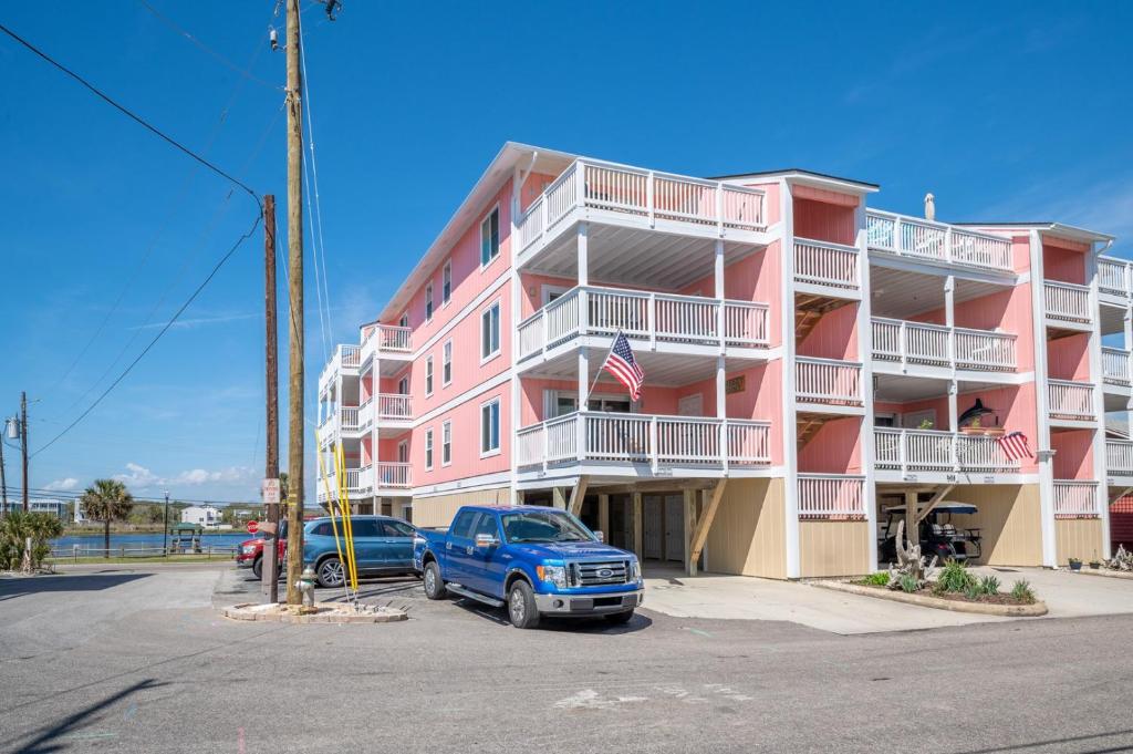 un edificio rosa con un camión azul estacionado en un estacionamiento en Sands II 1-J, en Carolina Beach