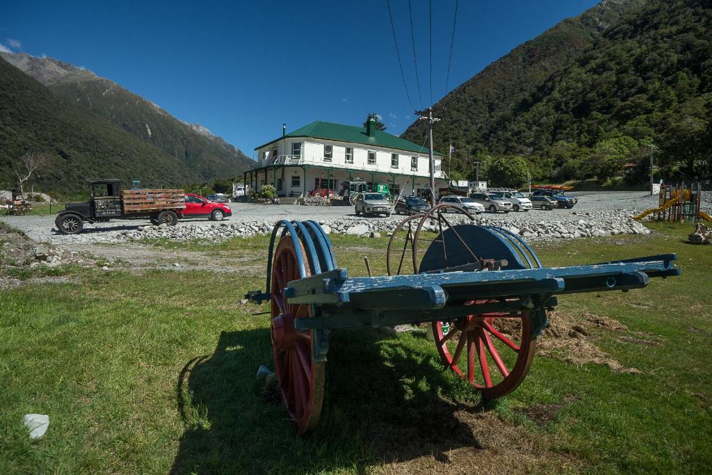 a cart sitting in the grass in front of a building at Otira Stagecoach Hotel in Otira