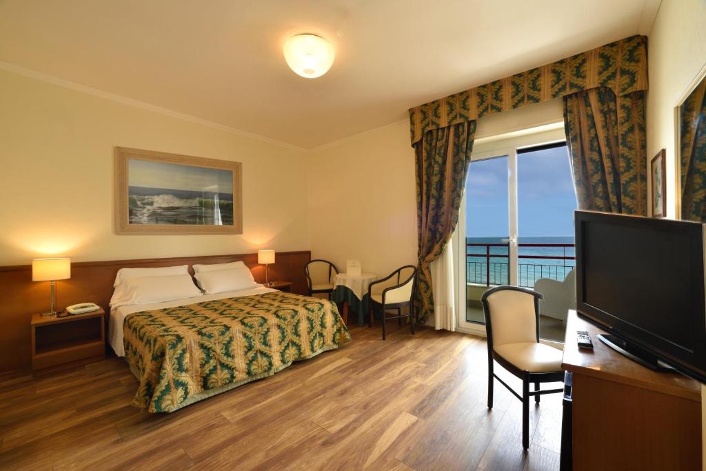 a hotel room with a bed and a flat screen tv at Hotel Europa & Concordia in Alassio