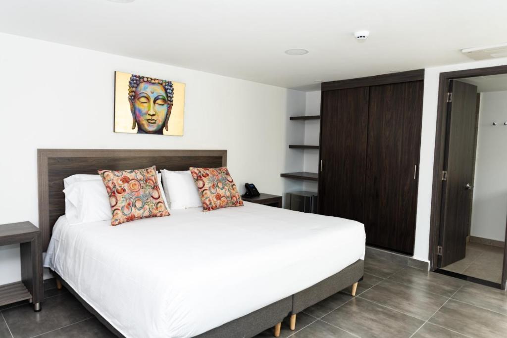 um quarto com uma grande cama branca num quarto em Hotel Qatar Cali em Cali