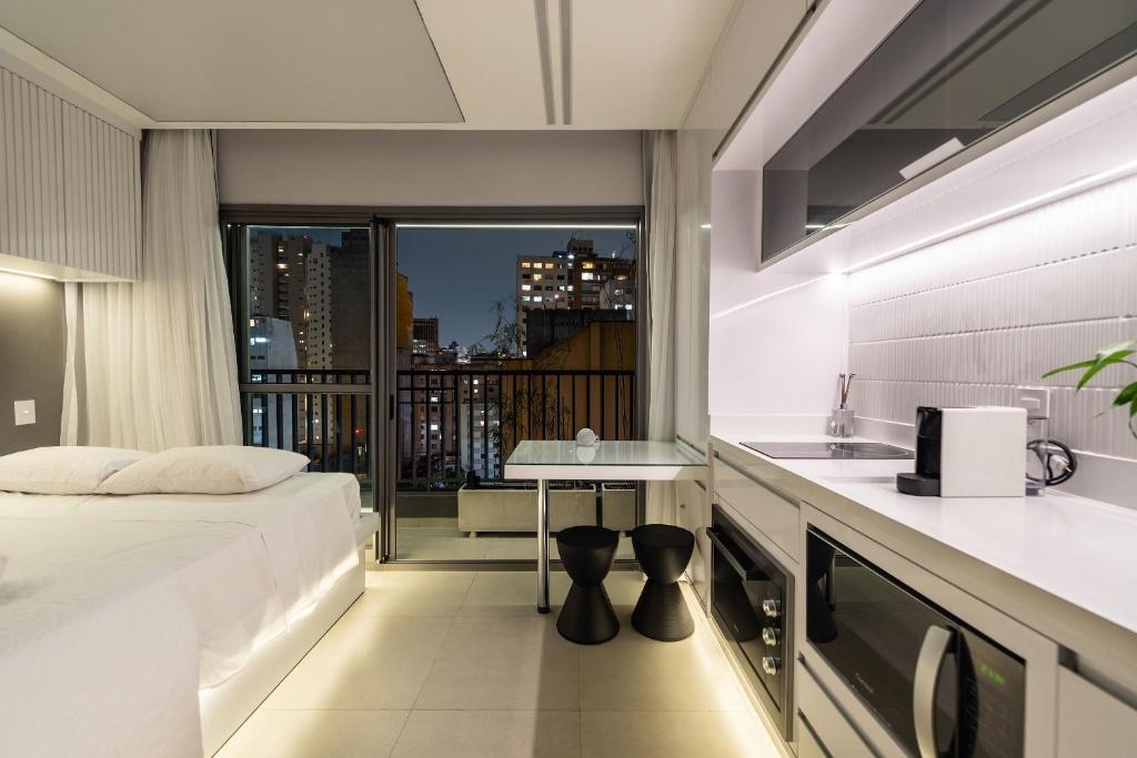a hotel room with a bed and a kitchen with a balcony at VNC13 Conforto e Estilo Perto do Metrô Anhangabaú in Sao Paulo