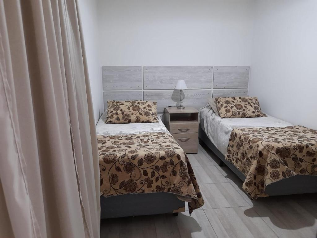 1 dormitorio con 2 camas y mesita de noche con lámpara en Monseñor Fagnano 592 "5" en Ushuaia