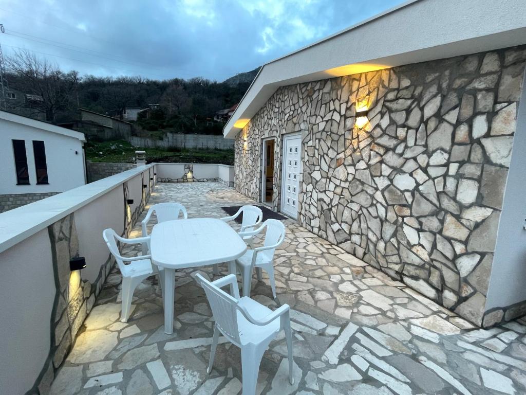 patio ze stołem i krzesłami na kamiennej ścianie w obiekcie Villa Tunaj Neu 2023 Novo,New w Barze
