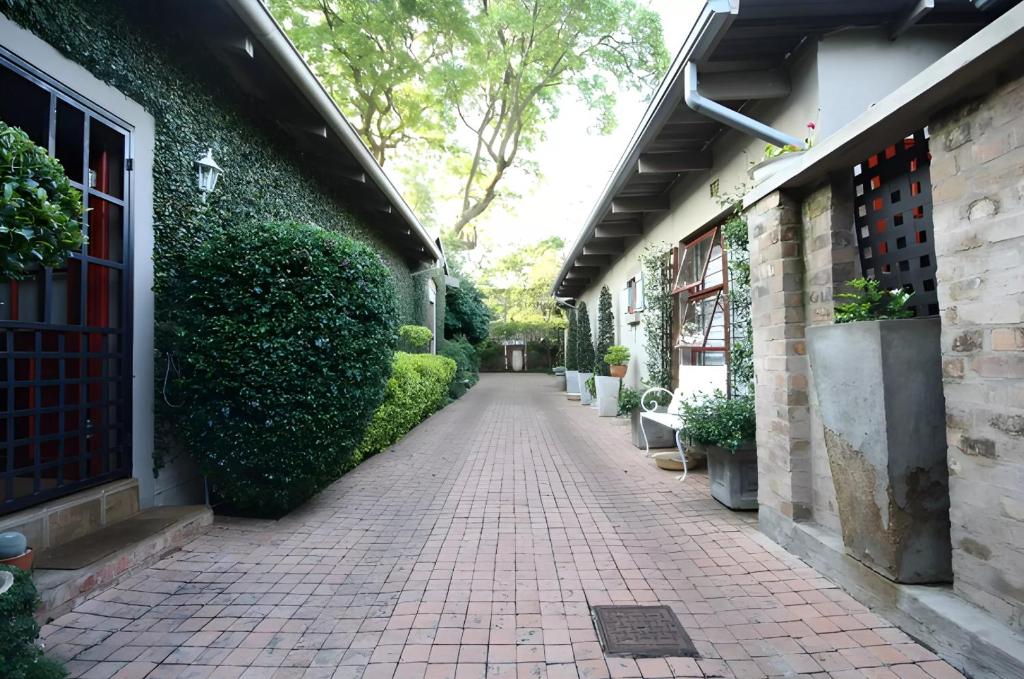 una pasarela de ladrillo junto a un edificio con plantas en Ambiance Guesthouse, en Pretoria