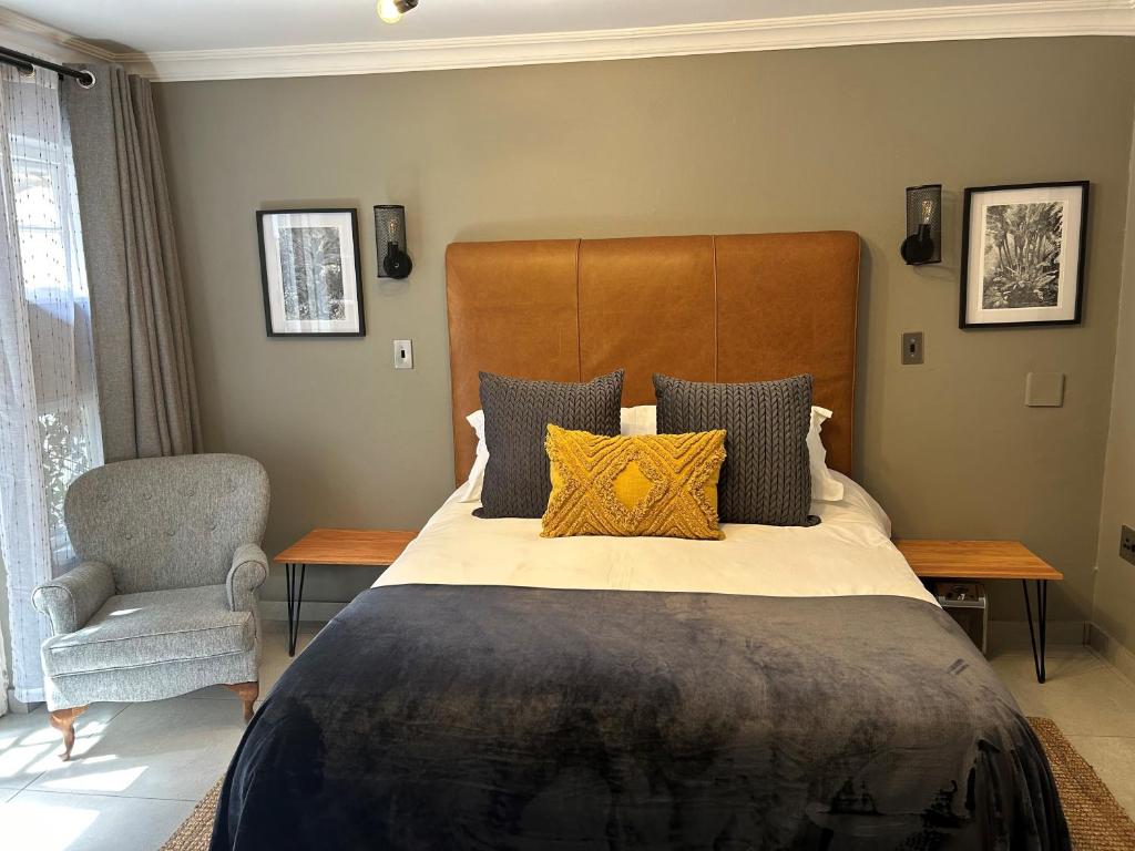 een slaapkamer met een groot bed en een stoel bij Battiss Guest House in Pretoria