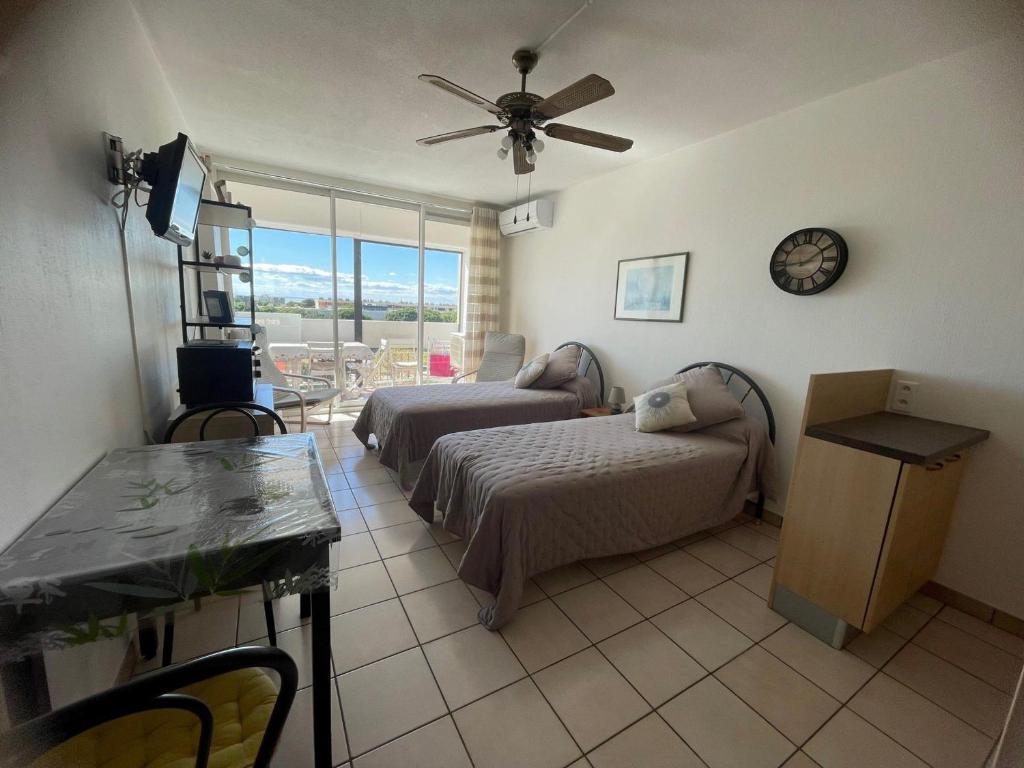 une chambre d'hôtel avec deux lits et une table dans l'établissement Charmant T2 avec balcon, clim et animaux admis à Balaruc-les-Bains - FR-1-503-85, à Balaruc-les-Bains