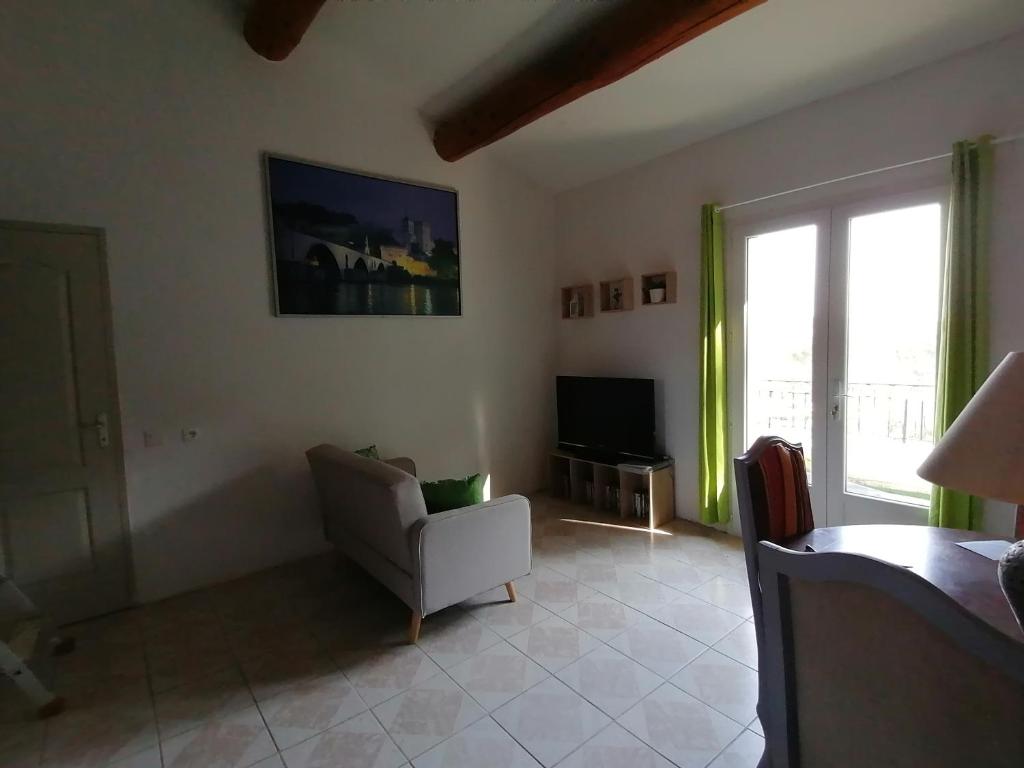 ein Wohnzimmer mit einem Stuhl und einem TV in der Unterkunft Le Tavan in Crillon-le-Brave