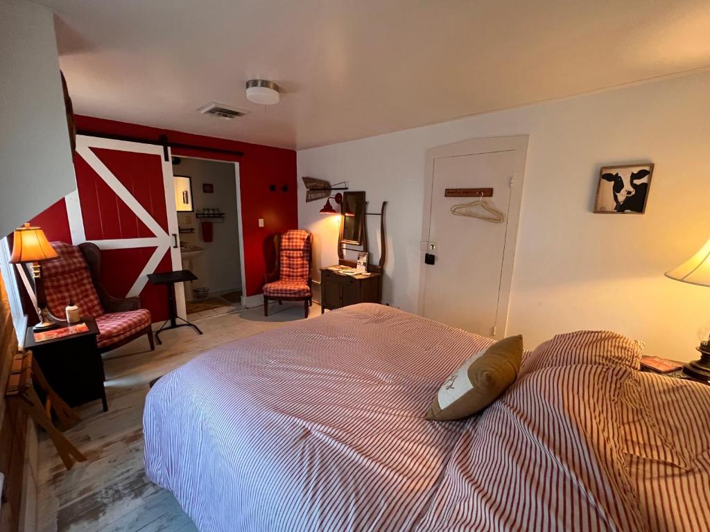 a bedroom with a bed and two chairs at The FarmHouse Inn Bed and Breakfast in Nappanee