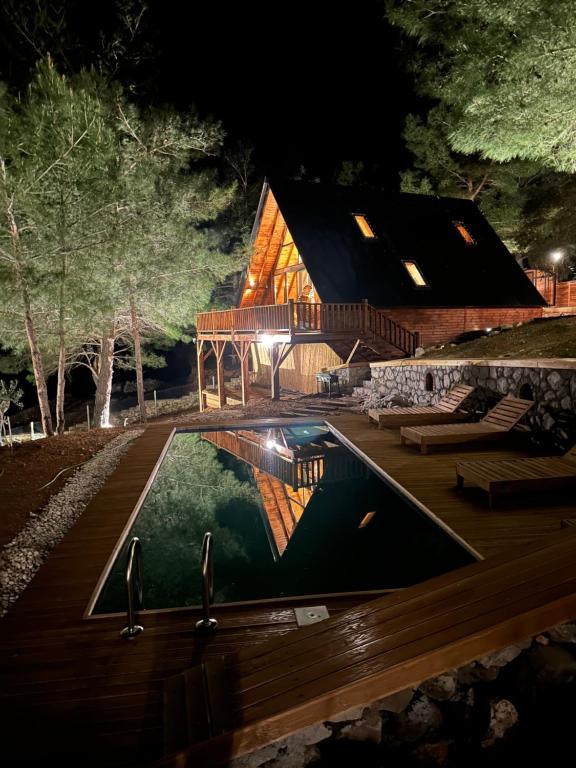 una casa con piscina por la noche en Panurlawoodenhouse özel havuz& sauna mavi en Urla