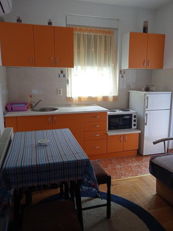a kitchen with orange cabinets and a table and a refrigerator at Benvenuto in Vrnjačka Banja
