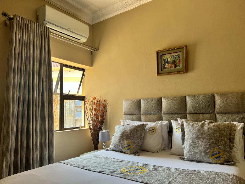 Schlafzimmer mit einem großen Bett und einem Fenster in der Unterkunft Aerodrome Lodge and Conference Centre in Benoni