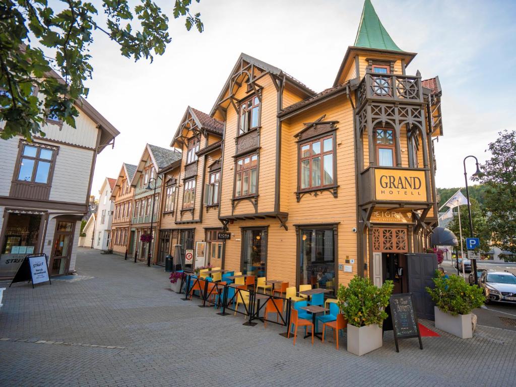 un edificio en una calle con mesas y sillas en Grand Hotel Egersund, en Egersund