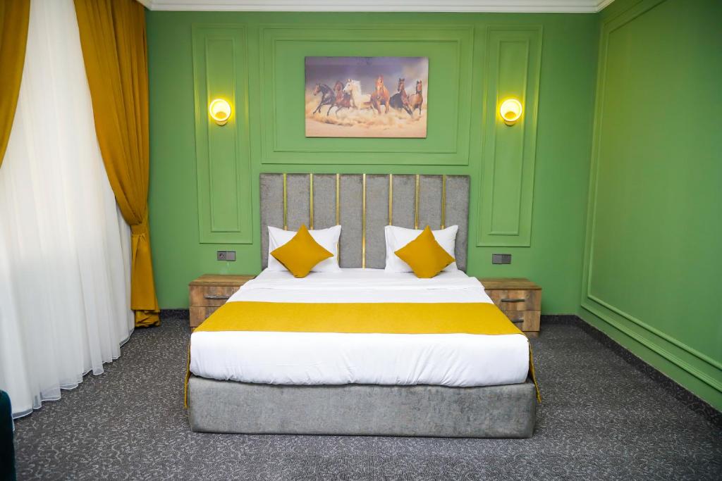 a bedroom with green walls and a bed with yellow pillows at Anatolia Hotel Baku in Baku