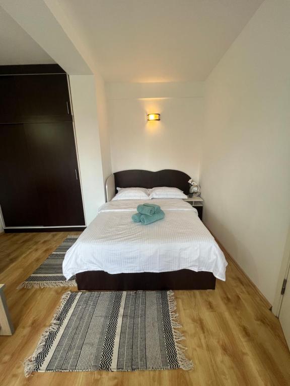 1 dormitorio con 1 cama con manta blanca y alfombra en Miha Residence, en Arad